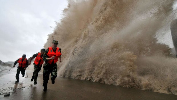 Troops are forced to run as a huge wave hits the sea wall in Wenling.