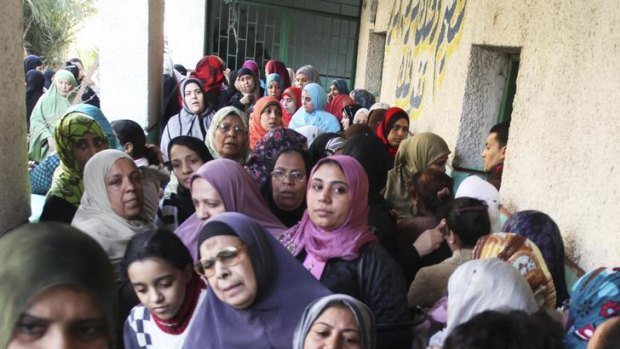 Women wait outside a polling station to cast their votes.