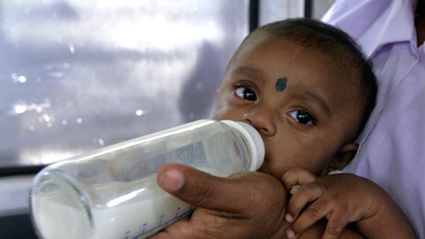 A baby drinks milk from a bottle in Sri Lanka.