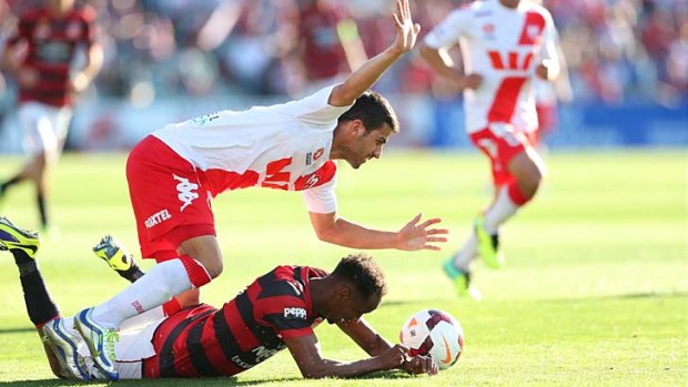 Grounded: Western Sydney's Youssouf Hersi is brought down in a tight match against Melbourne Heart.