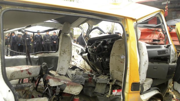 Chinese police officers and bystanders look at a kindergarten minibus which collided head-on with a truck loaded with coal.