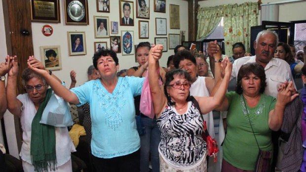 Relatives of Edgar Tamayo Arias pray in his parents’ house.