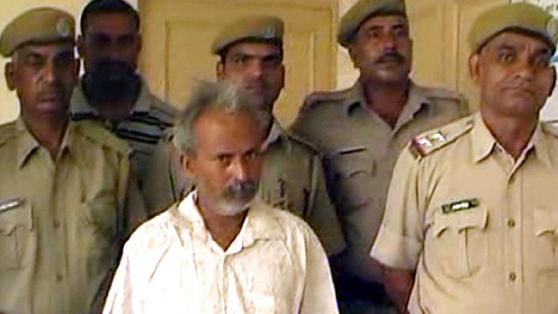 A screenshot shows Indian marble miner Oghad Singh (centre) in police custody after turning himself in following the brutal attack on his daughter.