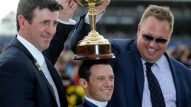That winning feeling ... Trainer Robert Hickmott and Nick Williams hold the Melbourne Cup up over Brett Prebble's head.