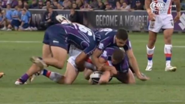 The tackle: Alex McKinnon is crushed under three Storm defenders.