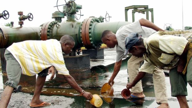 Nigerians scoop spilled crude oil from the Bomu flow station at Kederein Ogoniland, in the Niger Delta area of Nigeria in 2003.