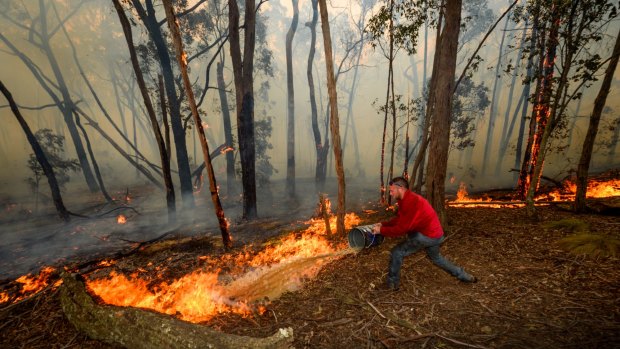 Adam Watkins working with friends to save his home near Lancefield, north of Melbourne, earlier this month.