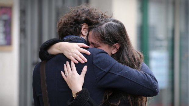A couple embrace after laying flowers at the La Belle Equipe cafe on Saturday.