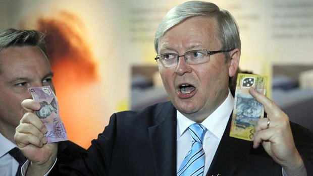Take note: Kevin Rudd uses cash to make a point at Westmead Hospital on Sunday as Treasurer Chris Bowen watches.