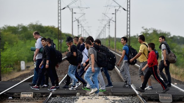 Hundreds of migrants walk from  Hegyshalom railway station to a holding centre on the border with Austria after Hungarian authorities closed the railway track crossing on Monday.