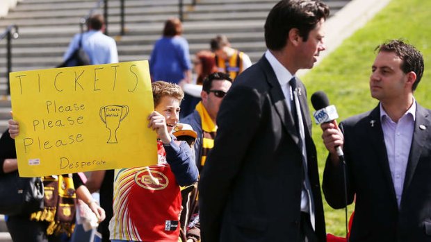 A fan seeks tickets as AFL CEO Gill McLachlan is interviewed outside the MCG.