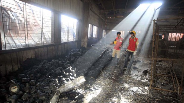 Bangladeshi rescue workers look on at the scene following a blaze that engulfed a garment factory.