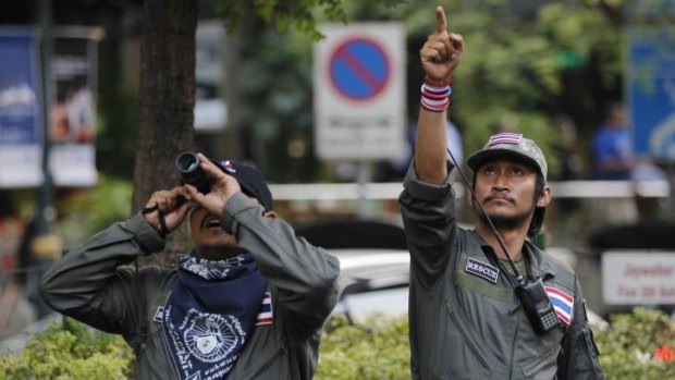 Security guards of the anti-government movement scan rooftops for possible threats on a marching route in Bangkok, Thailand.