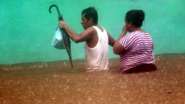 A couple wades in a flooded street in Acapulco, Mexico, after it was hit by Hurricane Ingrid and Tropical Storm Manuel. At least 20 people have been killed and thousands forced to evacuate their homes.