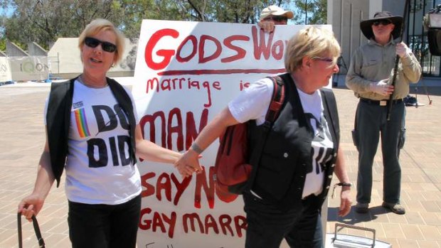 A couple embrace in front of same-sex marriage protesters at the High Court of Australia.