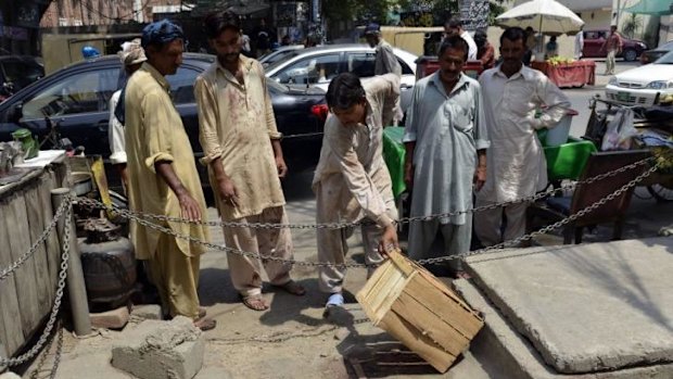 Pakistani bystanders look at the site, outside a Lahore court, where Farzana Parveen was allegedly beaten to death with bricks by members of her own family for marrying a man of her own choice.