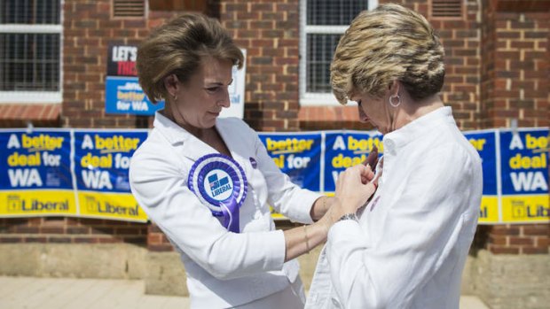 Pin-up girls: Liberal politicians (from left) Michaelia Cash and Julie Bishop get organised after voting in the WA Senate election on Saturday.