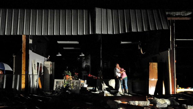Jeff and Melissa McKenzie embrace in the ruins of their florist and gift shop store in Columbia, Mississippi, after a tornado ripped through the city.