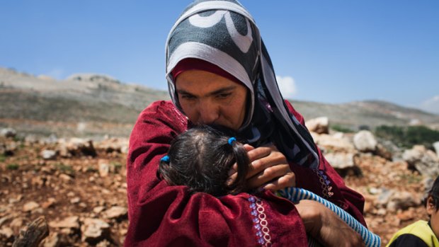 Syrian woman Lina kisses her two-year-old daughter outside her makeshift tent in Lebanon.