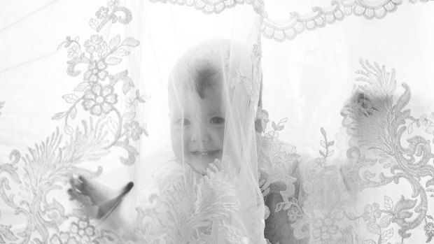Cheeky William Andrew peers out from under mum's Martina Liana dress. The Canberra Times, Wednesday 26 October 2016