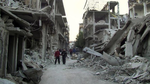 Rubble and ruin &#8230; Homs residents walk down a city street destroyed in missile strikes by Syrian warplanes this week.