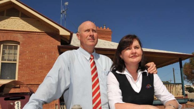 Hard to take ... Rick Liston and his wife, Cathie, yesterday in front of the Broken Hill house found to be riddled with asbestos.
