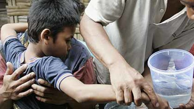 Muhammad Ponari (L), who locals believe possesses healing powers, dips his "magic stone" into a bottle of water.