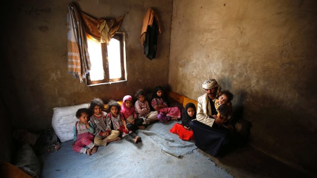 Faisal Ahmed, whose infant son, Udai Faisal, died of severe acute malnutrition, sits with his nine remaining children at his house in Hazyaz, Yemen. 