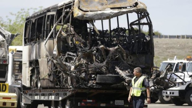A California Highway Patrol officer walks past the charred remains of the tour bus.