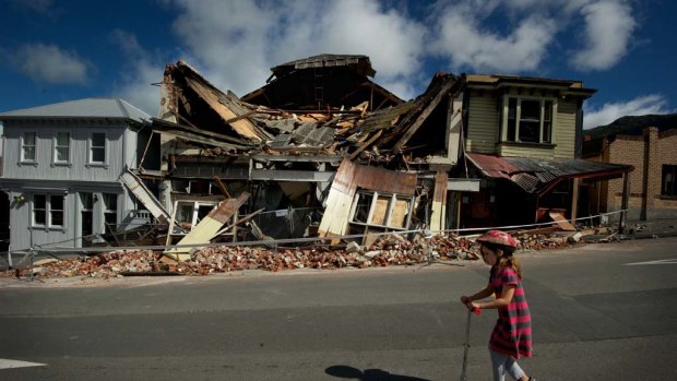 Recovery road ... Scarlett Corbett, 7, rides past the damaged theatre in the centre of Lyttelton.