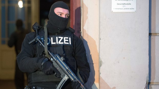 A member of a police task force stands in front of an apartment building where a raid took place against suspected jihadists in Berlin.