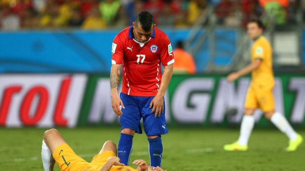 Mathew Leckie of Australia lies on the field as Gary Medel of Chile stands above him