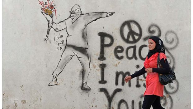 A young woman walks past graffiti in the rebel-held city of Minbej. Lawyers have relayed accusations against more than 140 people to rebel-established courts.