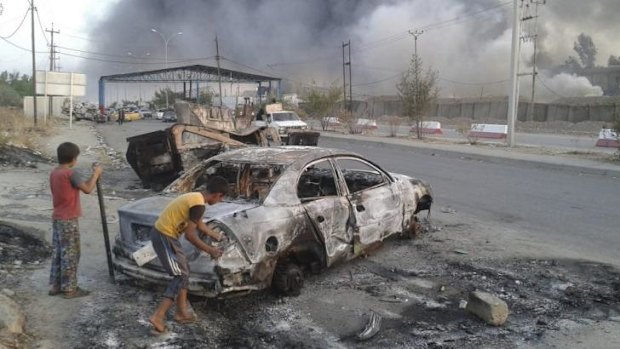 Children stand next to a burnt-out vehicle during clashes between Iraqi security forces and al-Qaeda-linked militants in the northern Iraq city of Mosul.