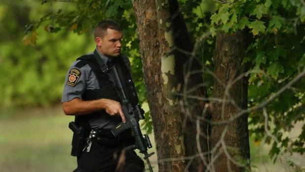 A Pennsylvania State Trooper walks in a wooded area near Route 447 in Price Township as he searches for suspected killer Eric Frein.
