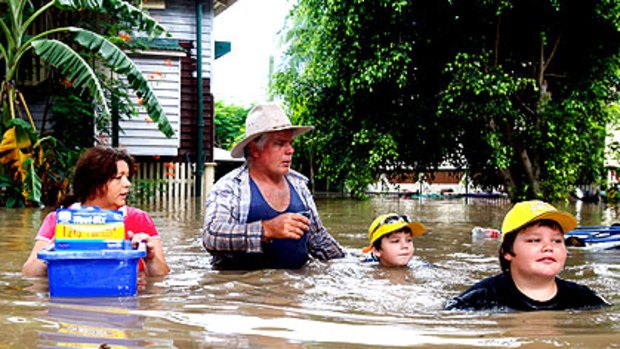 Paul Barnes and Mandy Greene, with their sons Bradley (left) and Patrick, struggle to reach their home in Rockhampton to find insurance documents.