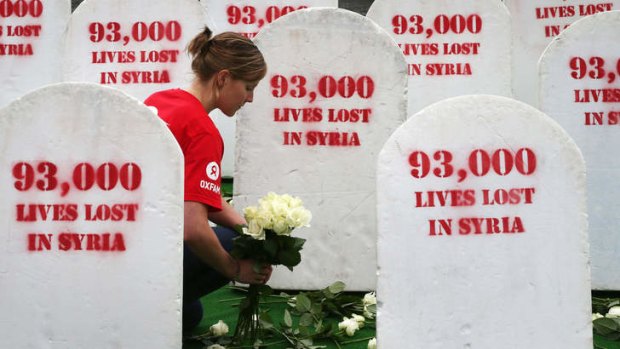 Rising toll: An Oxfam worker in Belfast places flowers among gravestones symbolising the dead in the civil war.