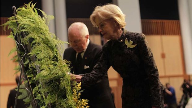 Governor General Quentin Bryce adds a sprig of wattle and frangipani to a wreath at the memorial services for the 10th anniversary of the Bali bombing at Parliament House, Canberra.