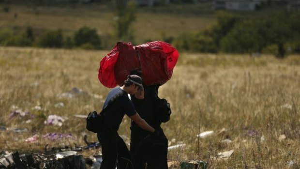 A suitcase wrapped in red plastic is recovered from the MH17 crash wreckage.