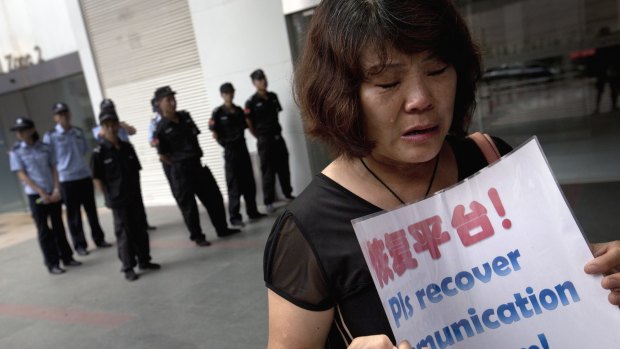 Hu Xiufang, a relative of passengers aboard the missing flight, holds a placard as she weeps outside the Malaysia Airlines office in Beijing.