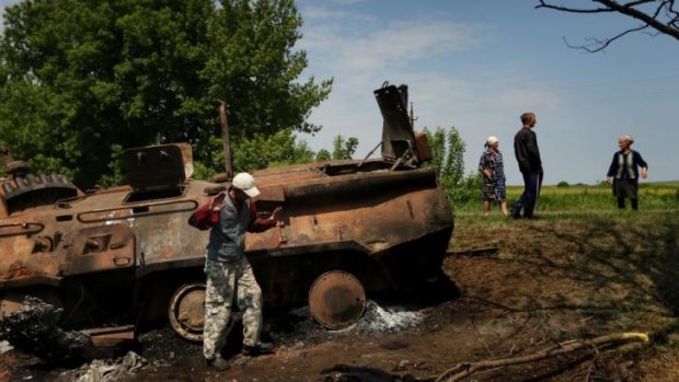 Locals stand near remains of a destroyed Ukrainian APC.