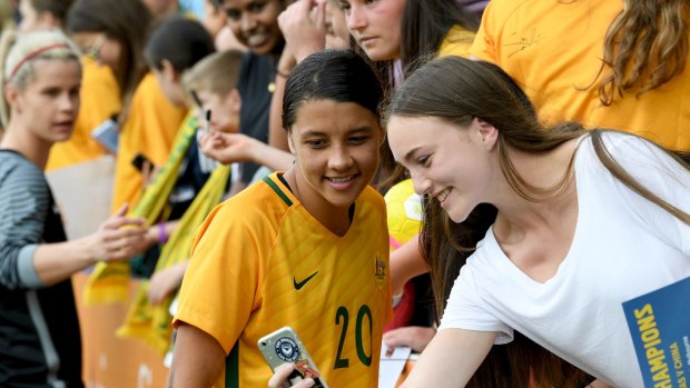Matildas star striker Sam Kerr takes a photo with a fan. 