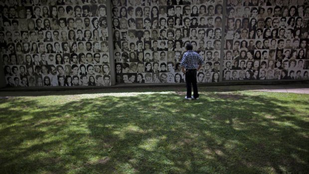 A visitor looks at pictures of Argentina's disappeared covering a wall of the the former Argentine Navy School of Mechanics.