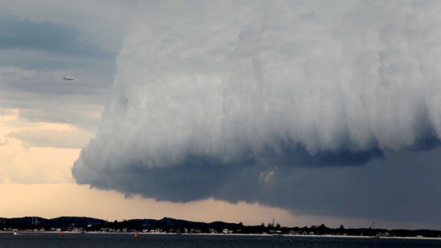 Qantas plane approaches a storm over the third runway at Sydney Airport, Botany Bay.