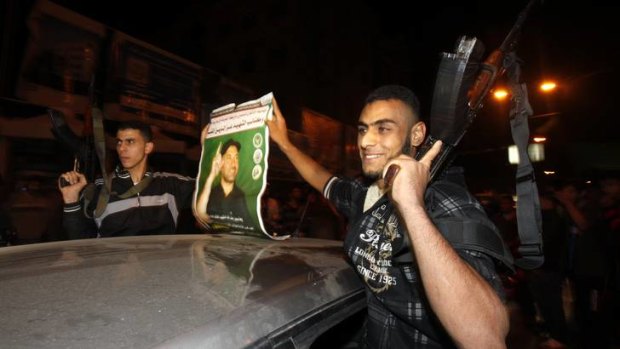 Uneasy peace ... celebrating Palestinian gunmen hold a poster of the Hamas military chief Ahmed al-Jabari, whose death in an Israeli air strike last week helped trigger the conflict.