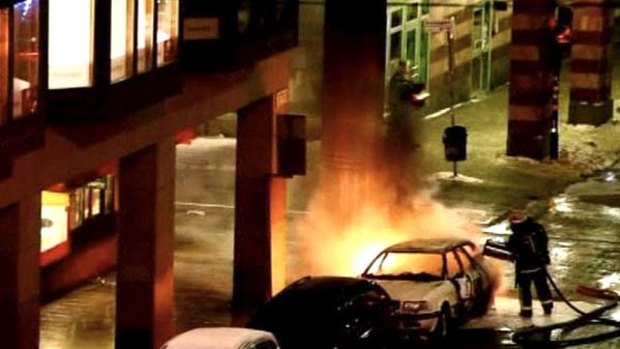 A still image taken from video shows firefighters attempting to put out the fire on a burning car in Stockholm.