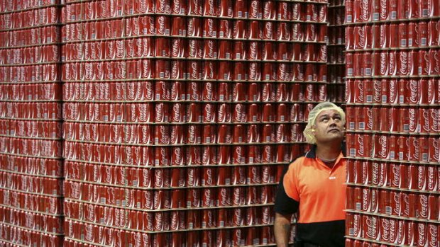 An employee inspects skids of Coca-Cola soft-drink ready for dispatch from the Coca-Cola Amatil bottling plant in Sydney, Australia.