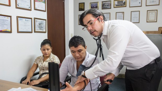Dr Ramon Garci­a-Trabanino talks with patients in his clinic in El Salvador's capital, San Salvador.