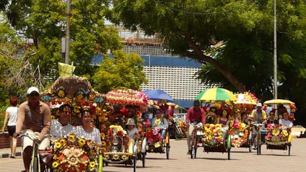 Colonial pace ... brightly decorated trishaws ferry tourists through the streets of Melaka.