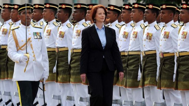 Heartless plan ...  Julia Gillard inspects a guard of honour in Malaysia.